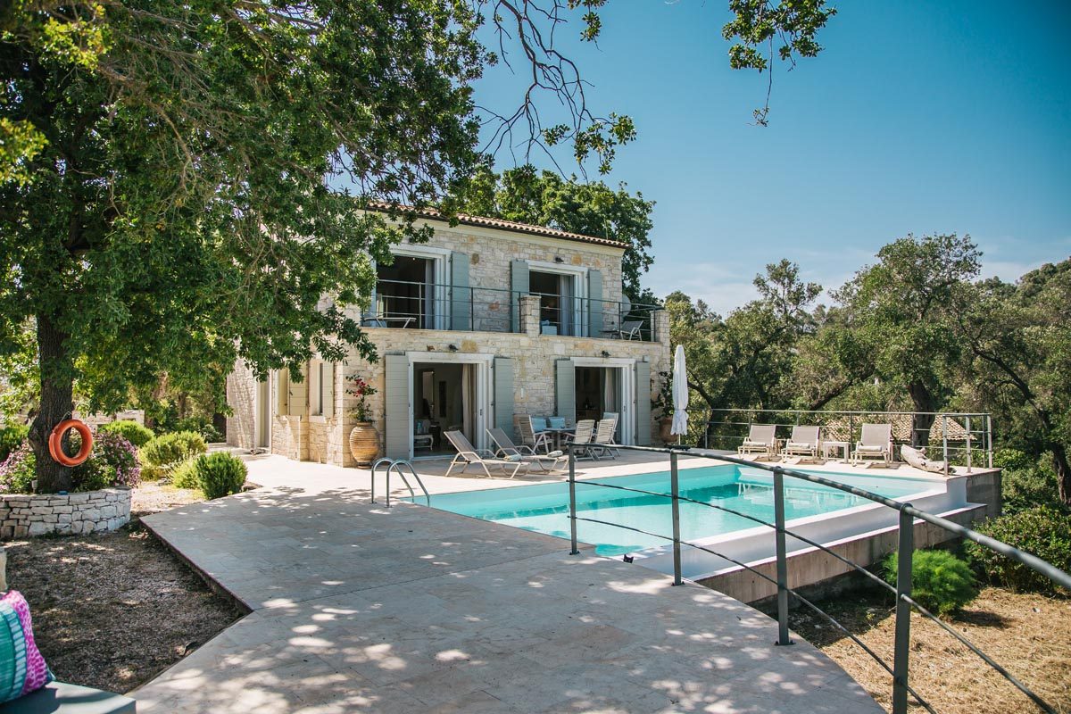 Mistral House exterior with the pool terrace and sunbeds in front of the stone facade